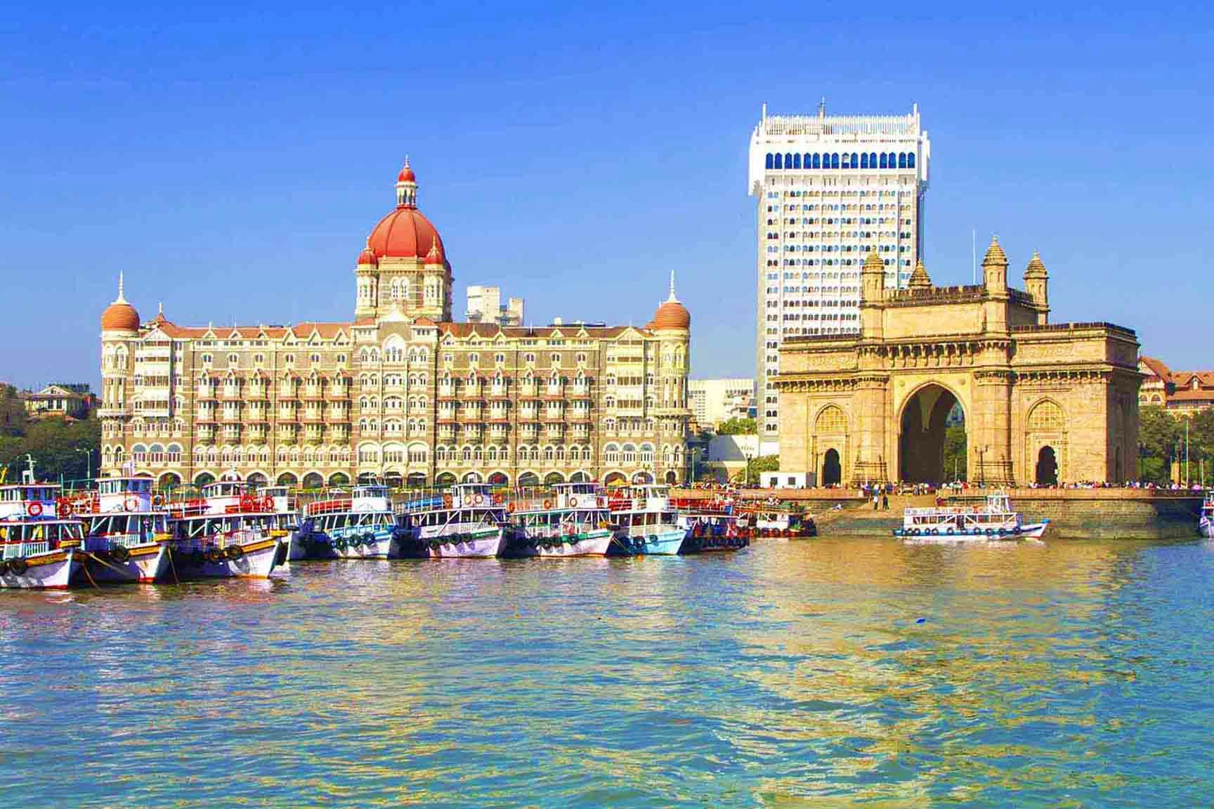 Mumbai waterfront with Gateway of India arch, historic colonial buildings, and fishing boats on Arabian Sea